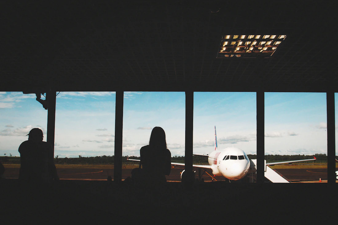 People watching an airliner from a terminal window